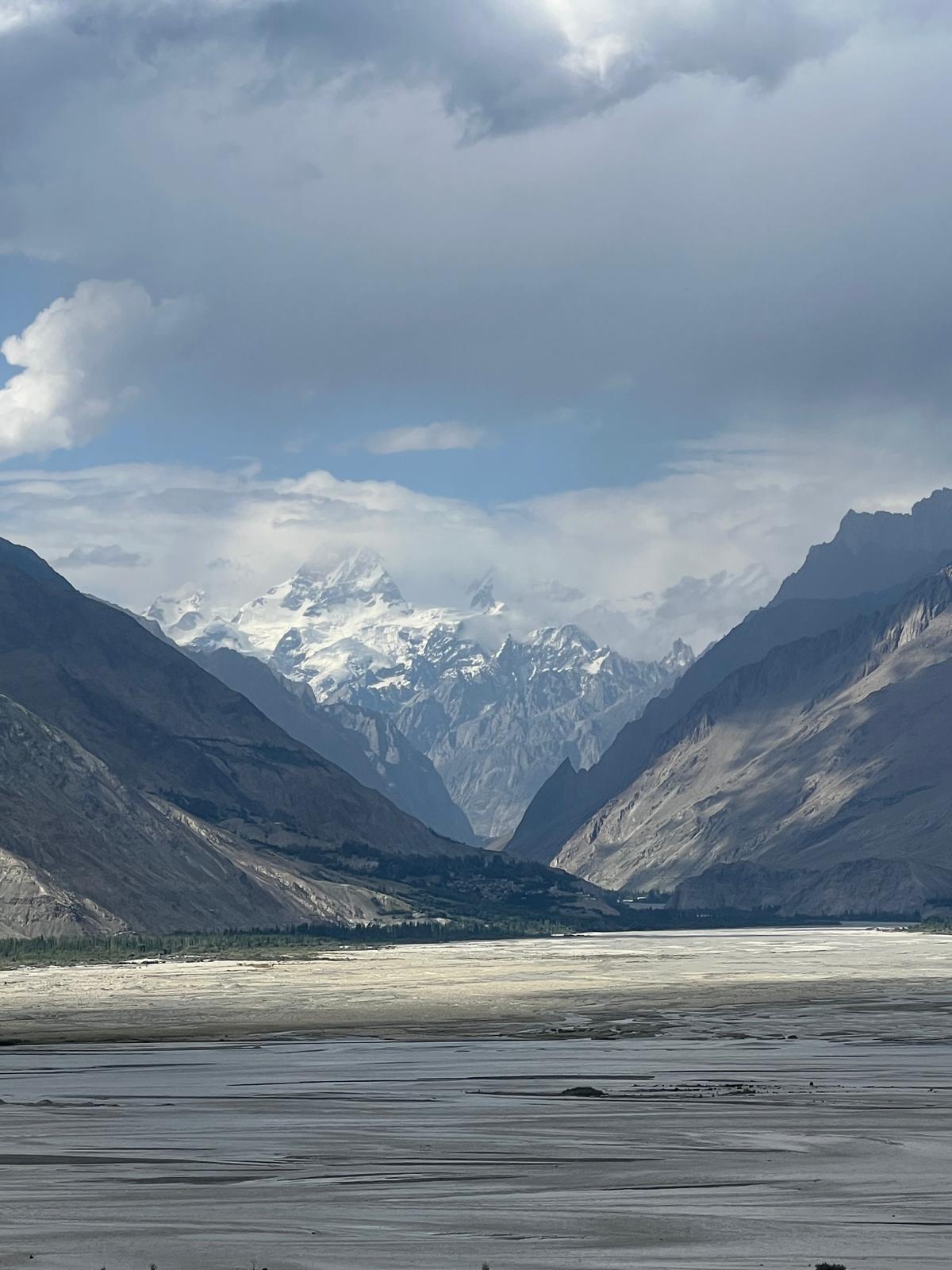 River flowing through a mountain valley with snow-covered peaks in northern Pakistan